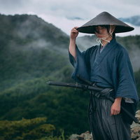 霧の山間で網代笠に右手を添える袴姿の侍の後ろ姿の写真