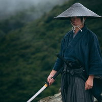 刀を振り下ろし静かに構えをとる侍の姿、網代笠と袴の和装武士の写真