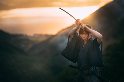 夕日を背に二本刀で上段の構えをとる侍のシルエット