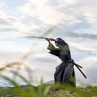 山頂の雲海背景で日本刀を構えて稽古に励む侍の写真
