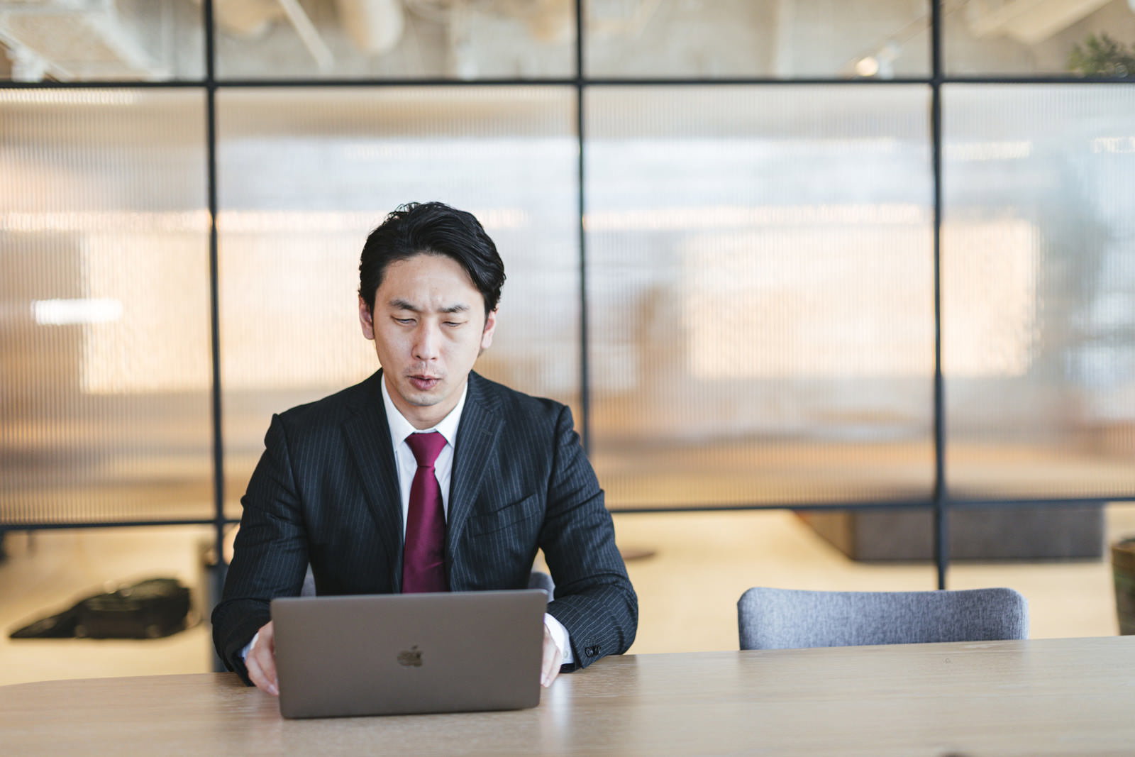 会議室でノートパソコンを使って作業するスーツ姿の男性会社員［モデル：大川竜弥］