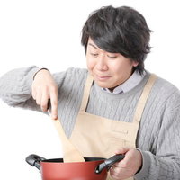 鍋に入ったスープをかき混ぜる男性の料理研究家の写真
