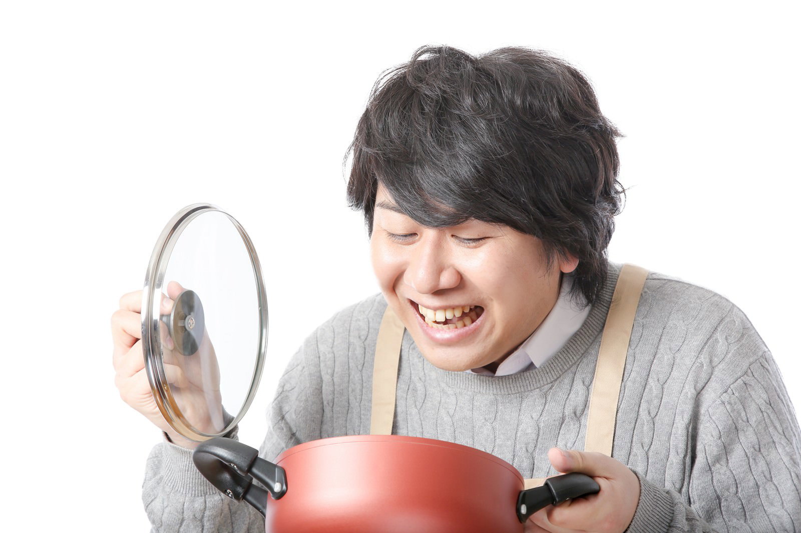 グレーのニットとベージュのエプロンを着た男性が、赤い鍋の蓋をあけて中身を確認している［モデル：あまのじゃく］