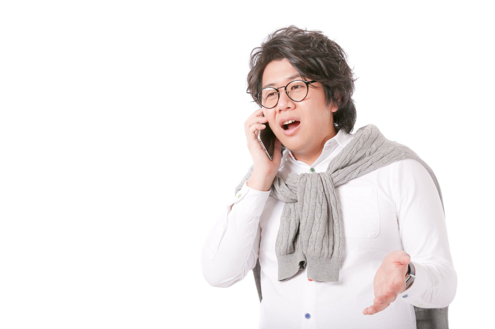 スマートフォンを持って通話しながら左手で身振りして説明する眼鏡の男性［モデル：あまのじゃく］