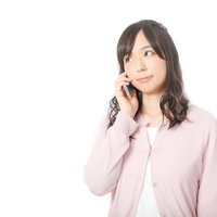 親切丁寧な電話サポートに笑顔が溢れる女性消費者、ピンクのカーディガン姿で通話中の写真
