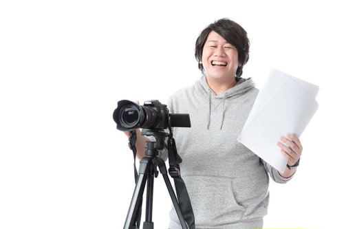 制作の現場で笑顔で絵コンテを手に映像機材を操作する男性ディレクター