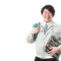 LANケーブルと基板を抱えて笑顔で作業する社内SE男性の写真