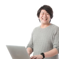 ノートパソコンを持ってにっこり笑う編集・ライター男性の写真