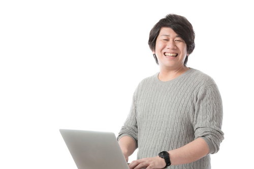ノートパソコンを持ってにっこり笑う編集・ライター男性