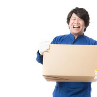 ダンボール箱を抱えて笑顔で仕事をする配送業務スタッフの写真