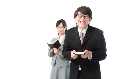 あらゆる業務を支える敏腕秘書が名刺を手に笑顔で立つ