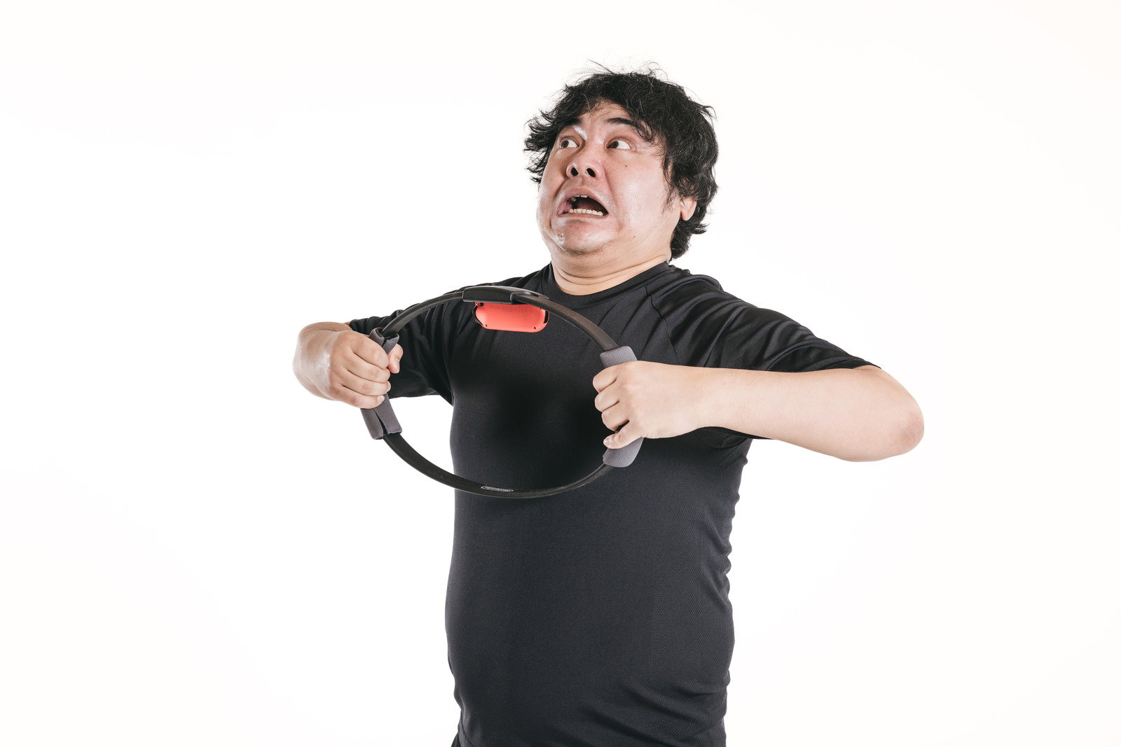 トレーニングリングを両手で引っ張り背筋を強化する男性［モデル：段田隼人］