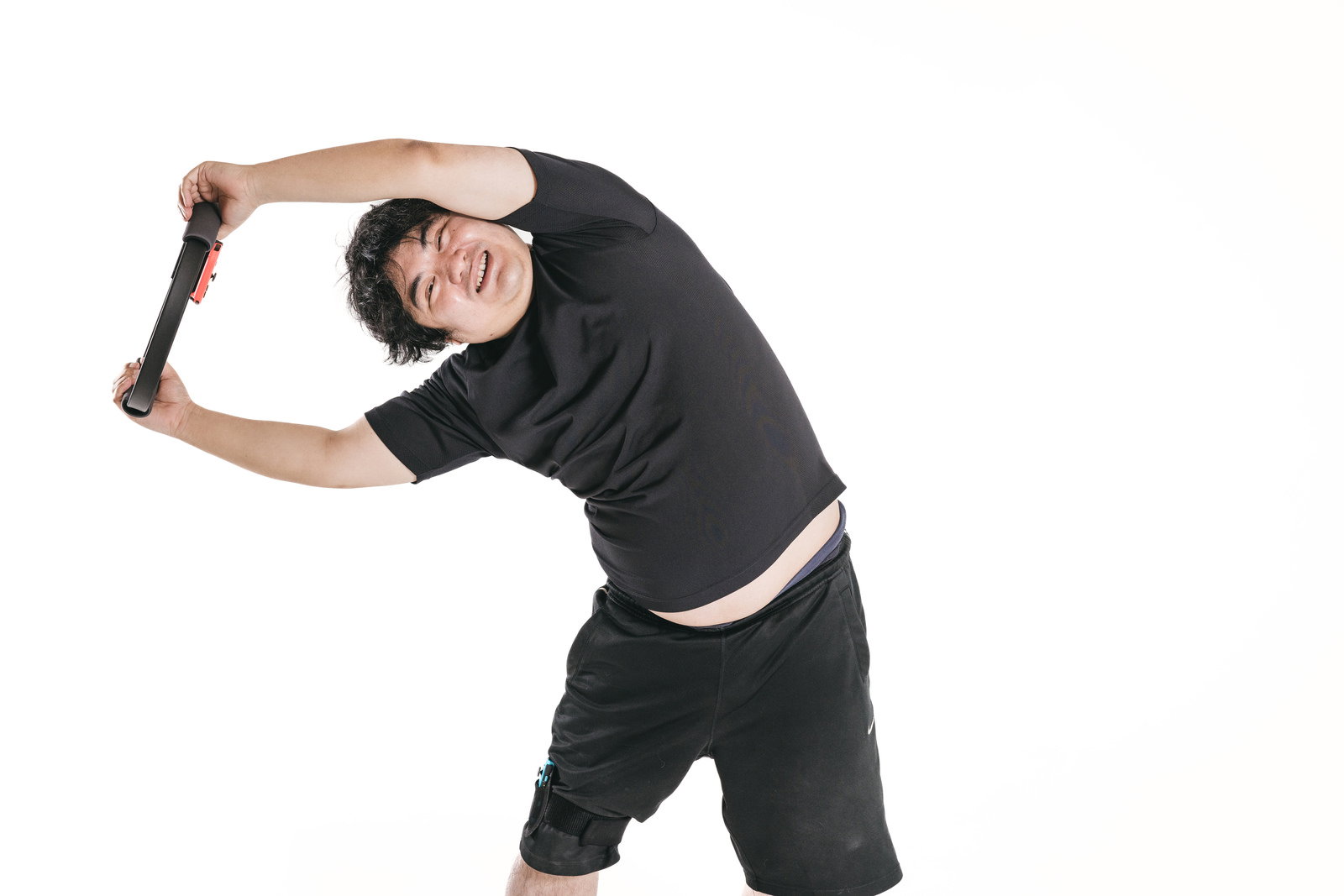 黒いTシャツを着た男性が右腕を上げて体を横に曲げてトレーニングしている［モデル：段田隼人］