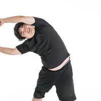 黒いTシャツで体を横に曲げるトレーニング中の男性の写真