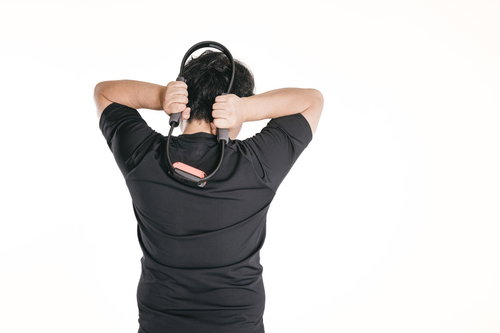 ヘッドフォンを首にかけて肩を上げる上腕三頭筋を鍛える男性