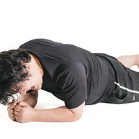 プランクの姿勢を続けるのがつらい男性のトレーニング姿の写真