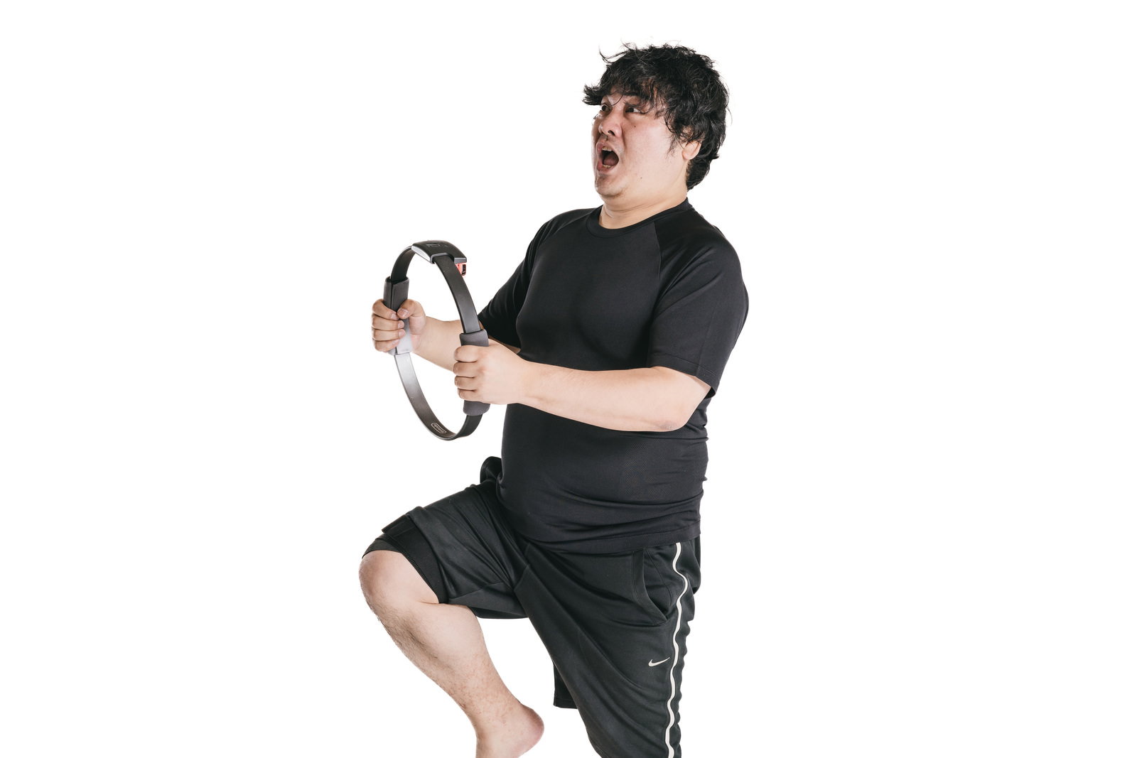 黒いリストバンドを握りながら腿を高く上げてトレーニングする男性［モデル：段田隼人］