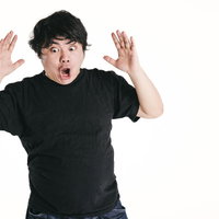 想定外でびっくりして両手を上げる男性の表情の写真