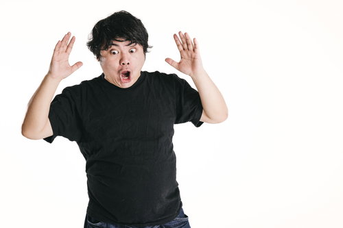 想定外でびっくりして両手を上げる男性の表情