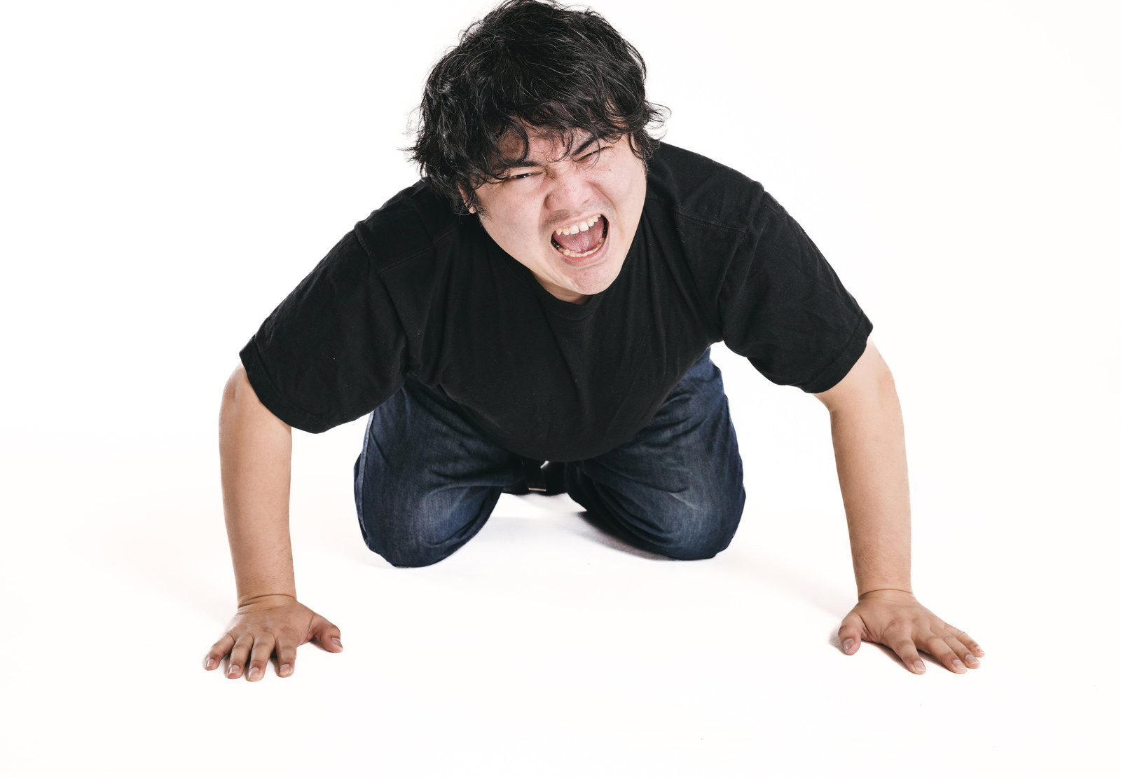 黒いTシャツを着た男性が両手と両膝を地面に付けて頭を下げながら口を開けて叫んでいる［モデル：段田隼人］