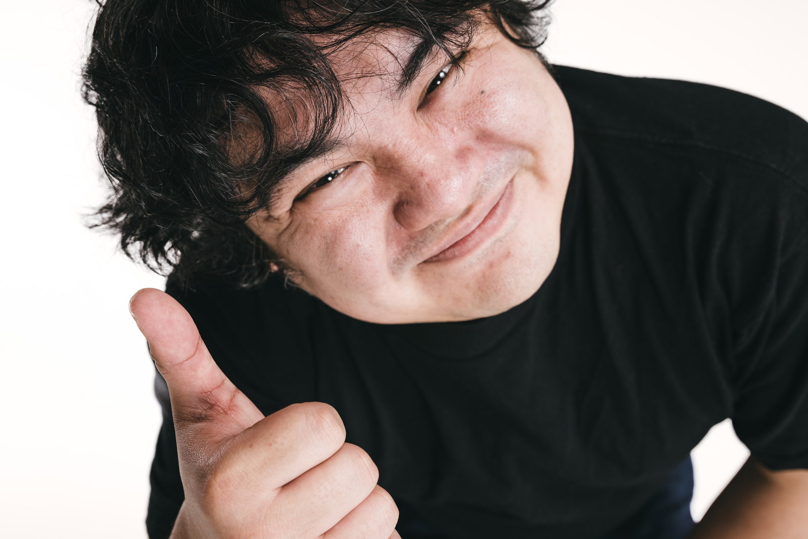 親指を立ててOKサインをする黒いTシャツの男性［モデル：段田隼人］