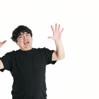 驚愕して両手を大きく挙げる男性の驚き顔リアクションの写真