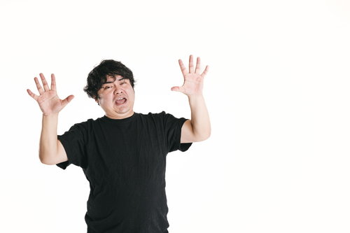 驚愕して両手を大きく挙げる男性の驚き顔リアクション
