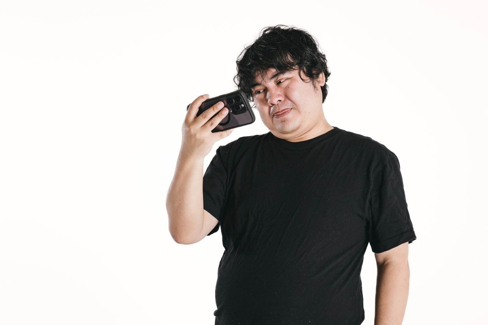 スマートフォンを耳に当てて大きく笑う黒いTシャツの男性［モデル：段田隼人］