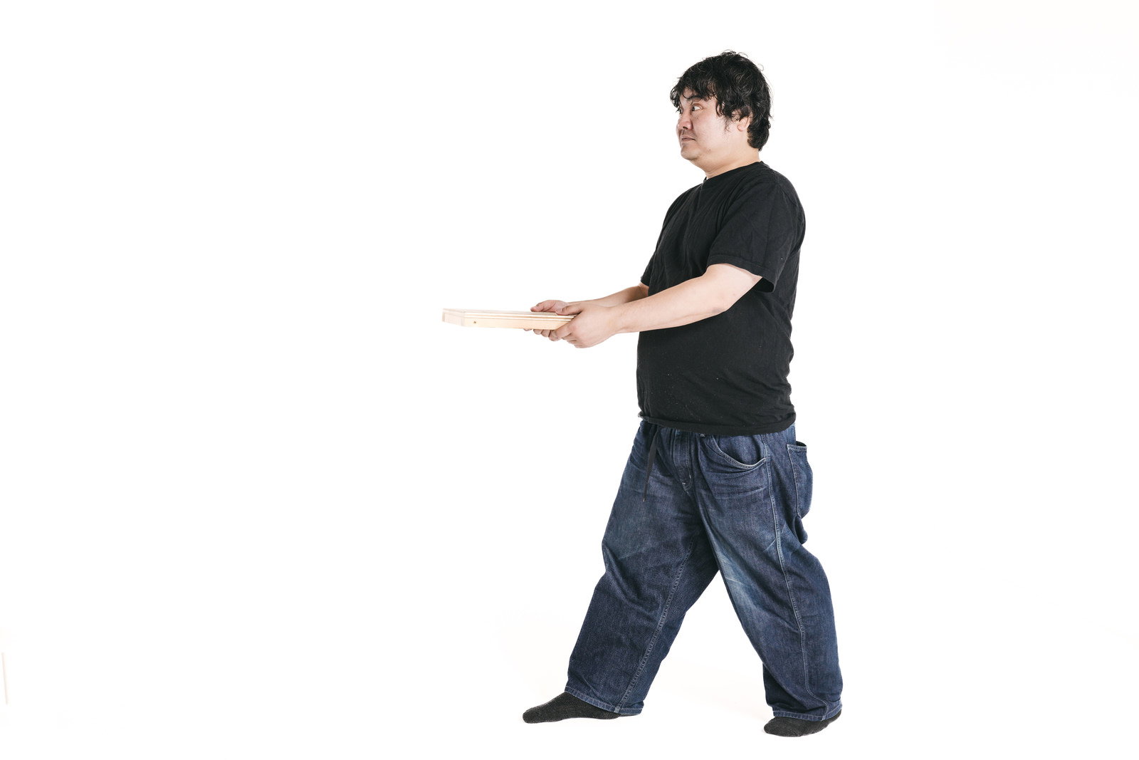 木製トレーを持ってポーズする黒いTシャツの男性［モデル：段田隼人］
