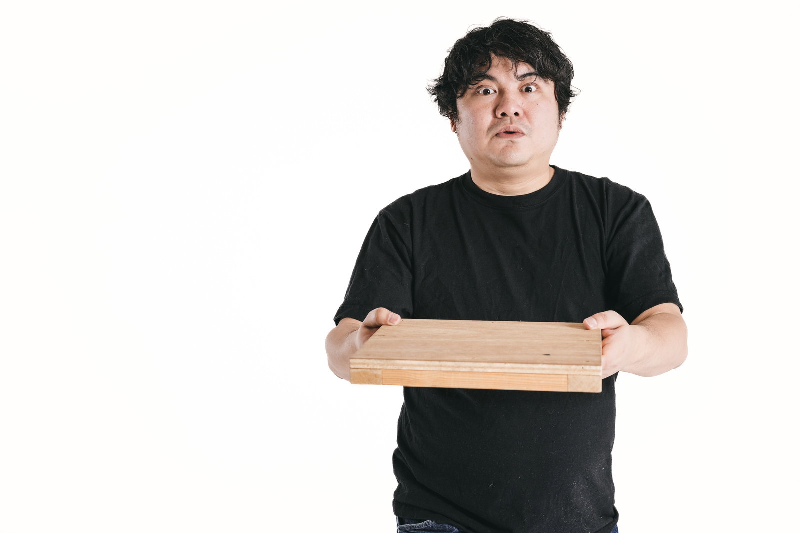 木製トレーを両手で持つ男性が配膳トレーニングをしている［モデル：段田隼人］