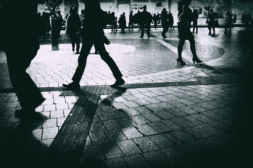 人が行き交うシルエット、粒状のノイズが際立つモノクロ