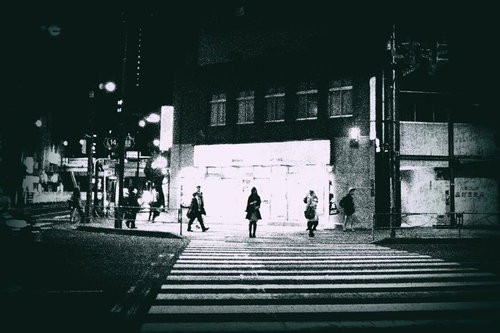 夜間の信号待ち、街頭灯に照らされた横断歩道で立つ人々