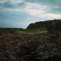 硫黄島の岩場に残る朽ちた陸軍トーチカと曇天の空の写真