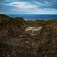 硫黄島の米軍施設跡塹壕から望む曇天の海岸線の写真