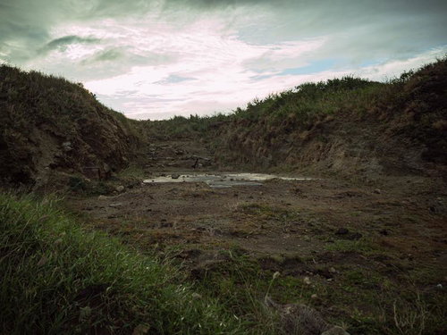 塹壕に残るコンクリートの遺構と曇り空の静寂