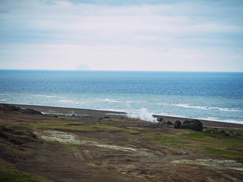 蒸気立つ海岸線と遠き北硫黄島の島影の写真