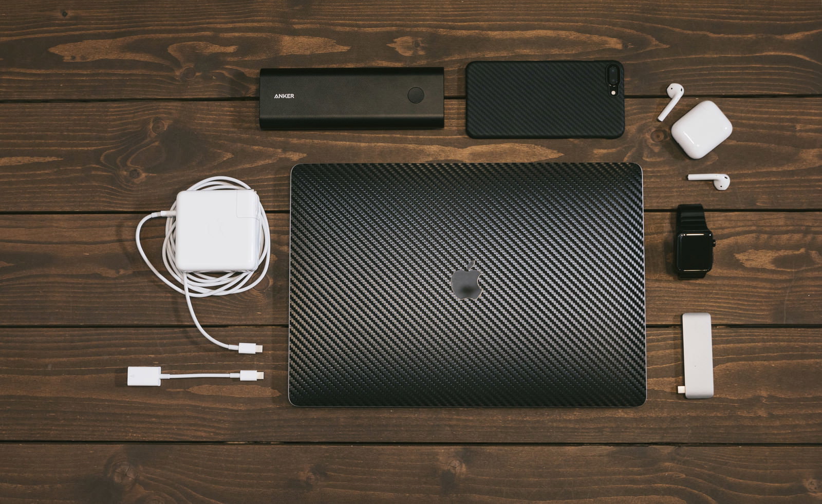木目テーブルにMacBookとAppleガジェットを並べた俯瞰写真