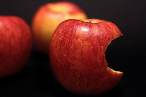 手前のかじられたリンゴにピントが合う3つの赤い林檎