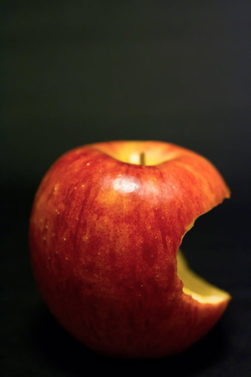 暗い背景の上の三日月形にかじられた赤い林檎