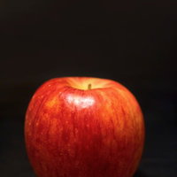 黒い布の上に置かれたつやのあるまんまる林檎の写真