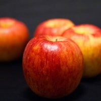 暗い面に並べた4個のまだら模様の赤いりんごの写真