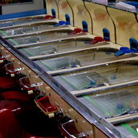 赤い椅子付きのスマートボール筐体が並ぶレトロなゲームセンターの写真