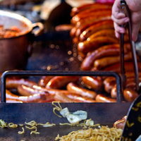鉄板の上のソーセージと焼きそばの屋台料理の写真