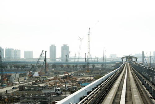 高架の鉄道線路と左側に広がる建設中の工事現場の都市風景