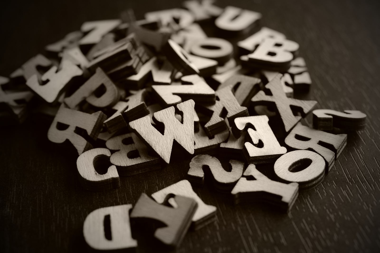 Scattered wooden alphabet and numbers on a dark surface