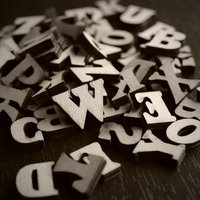 暗い背景に散らばる木製のアルファベットと英数字の写真