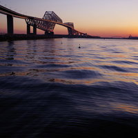 夕焼け色に染まる東京ゲートブリッジと東京湾の写真