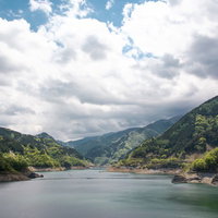 山に囲まれた穏やかなダム湖の風景の写真