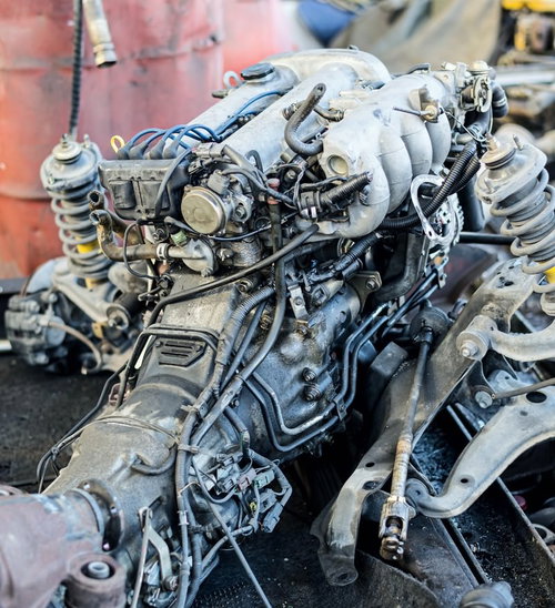 屋外に放置されたエンジンと足回り部品のスクラップ