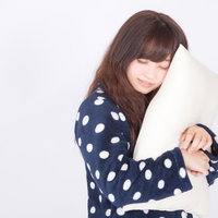 白いまくらを抱いて爆睡中の女性、気持ちよく熟睡している様子の写真